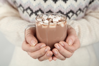 Photo of Woman in sweater holding cup of hot drink with marshmallows, closeup