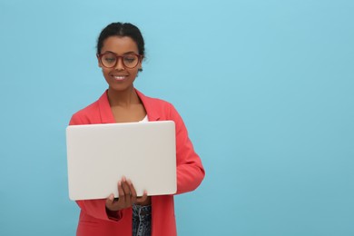 Photo of Smiling African American intern working on laptop against light blue background. Space for text