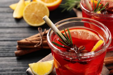 Photo of Aromatic punch drink and ingredients on black wooden table, closeup