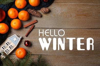 Image of Hello Winter greeting card. Flat lay composition with tangerines on wooden background