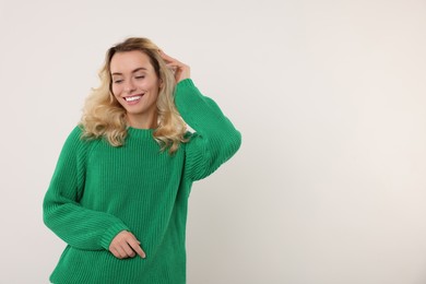 Happy woman in stylish warm sweater on white background. Space for text