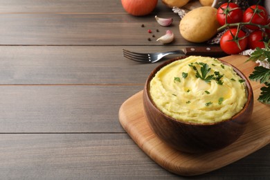 Photo of Bowl of freshly cooked mashed potatoes with parsley served on wooden table. Space for text
