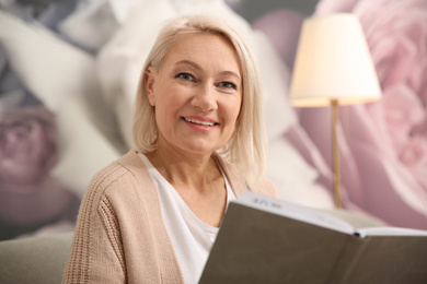 Photo of Beautiful mature woman reading book at home