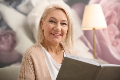 Beautiful mature woman reading book at home