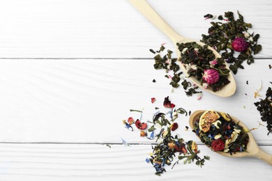 Photo of Spoons with dried herbal tea leaves and fruits on white wooden table, flat lay. Space for text