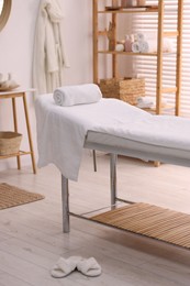 Comfortable massage table with clean towels in spa center