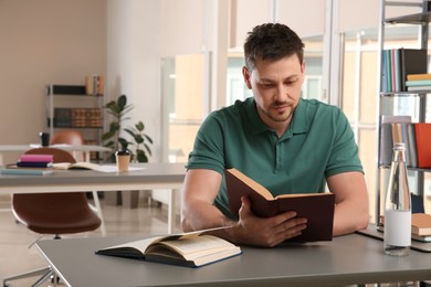 Man reading book at table in library