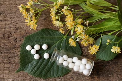 Photo of Bottle of homeopathic remedy, linden flowers and leaves on wooden background, flat lay