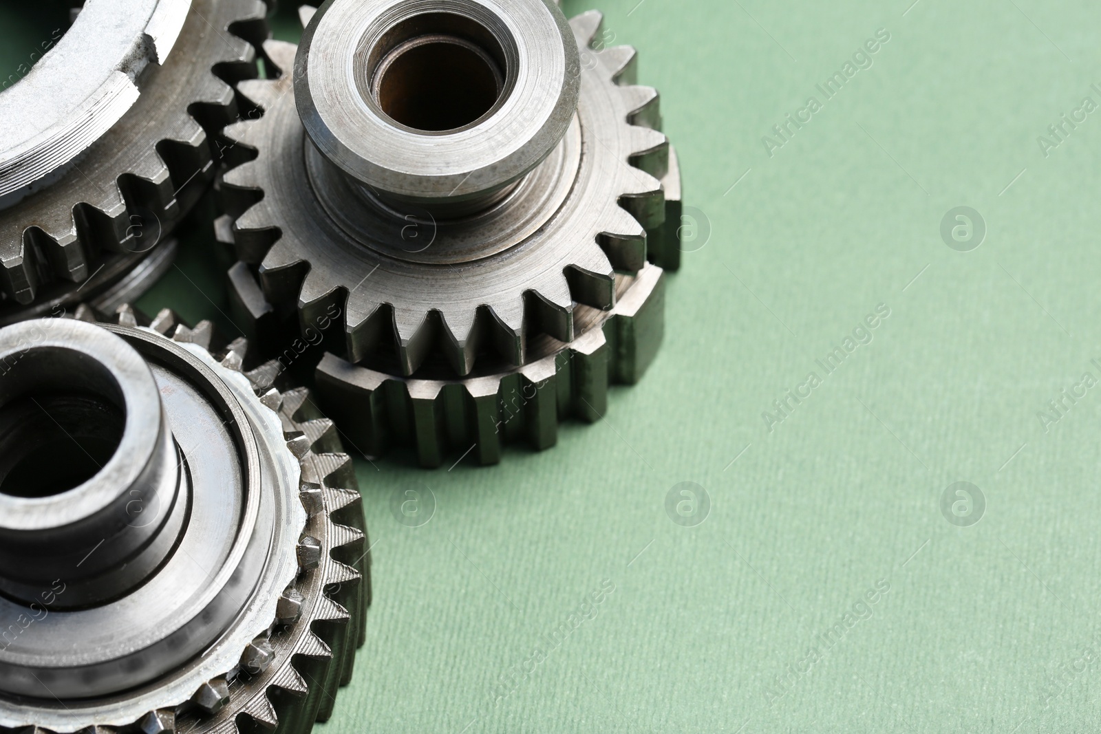 Photo of Different stainless steel gears on light green background, closeup. Space for text