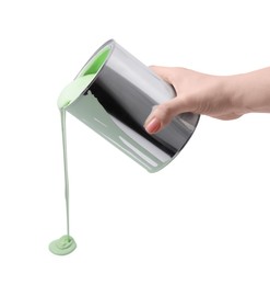 Woman pouring light green paint from can on white background, closeup