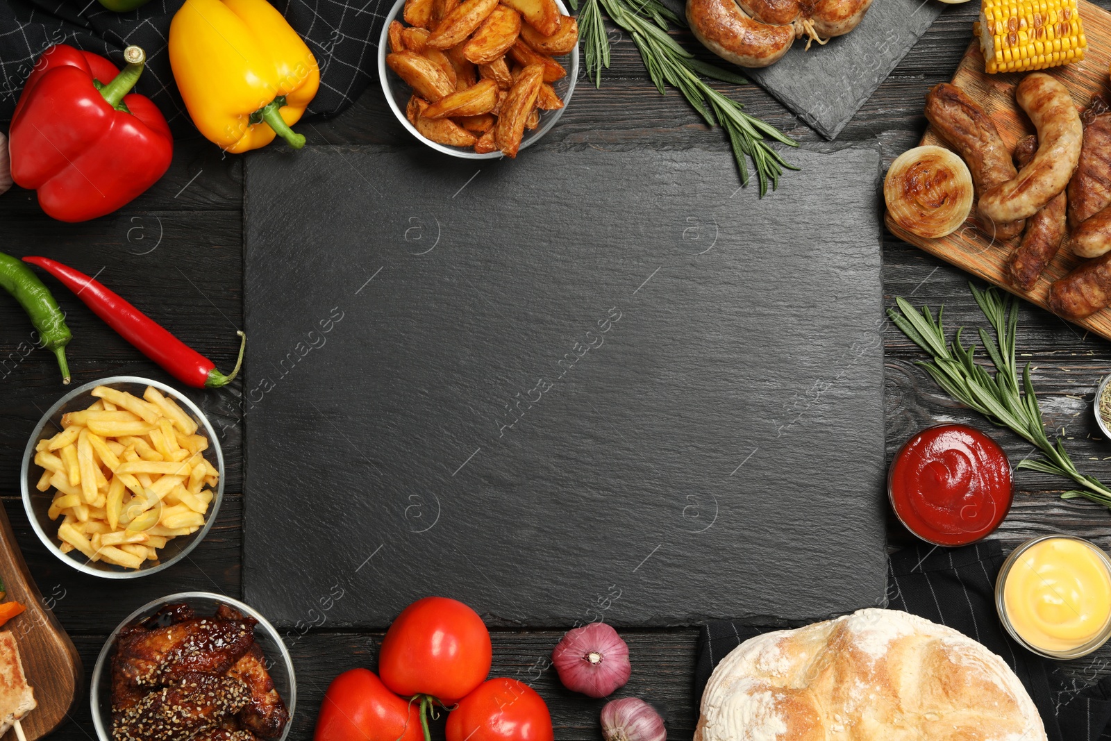 Photo of Flat lay composition with barbecued meat and vegetables on black wooden table. Space for text