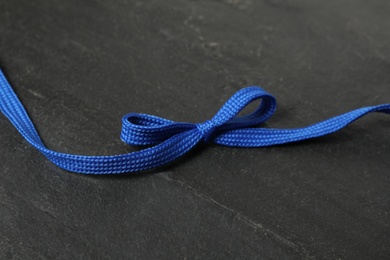 Photo of Blue shoelace on black slate background. Stylish accessory