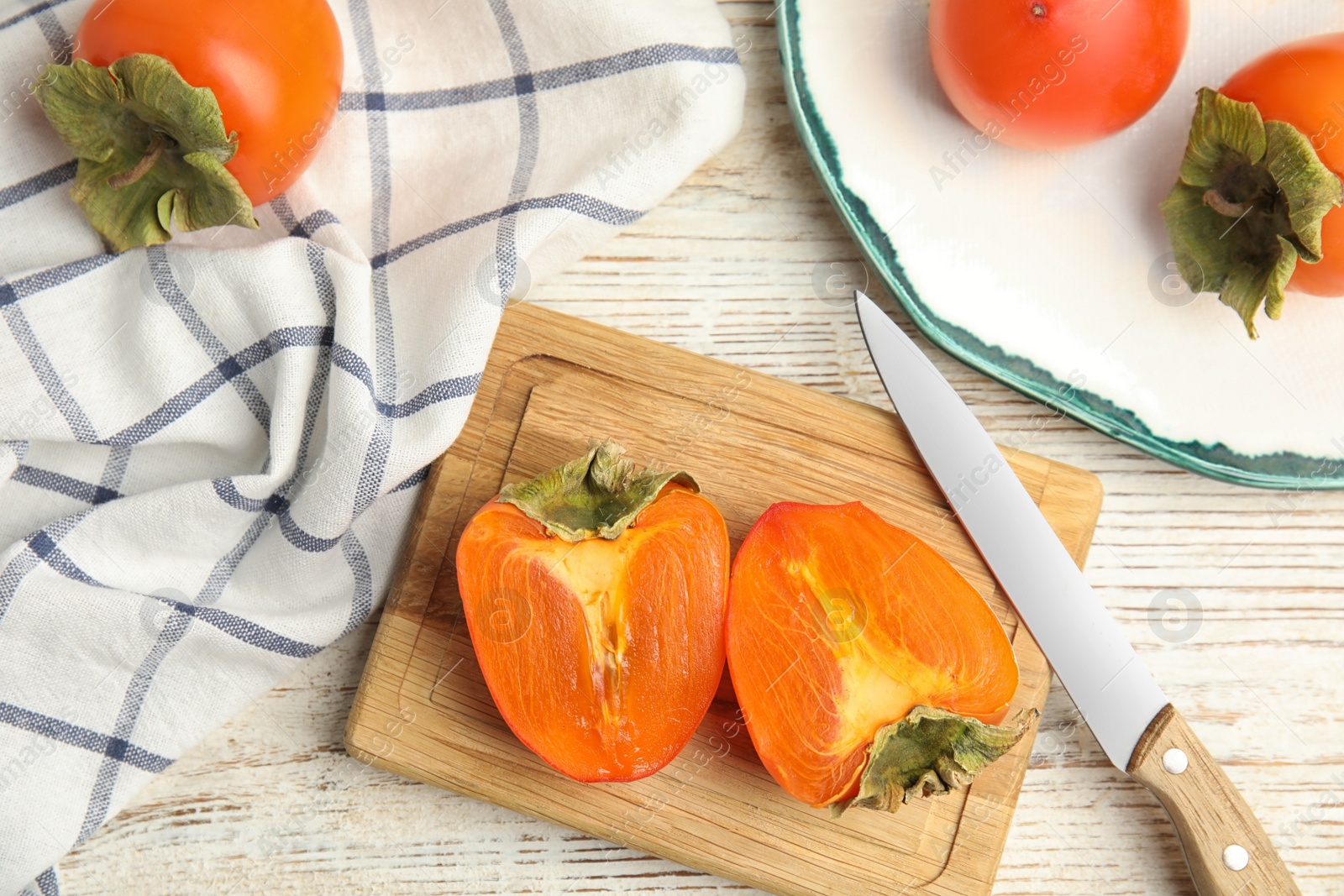 Photo of Tasty ripe persimmons on white wooden table, flat lay