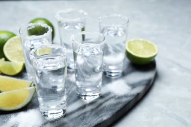 Photo of Mexican Tequila shots, lime slices and salt on grey marble table