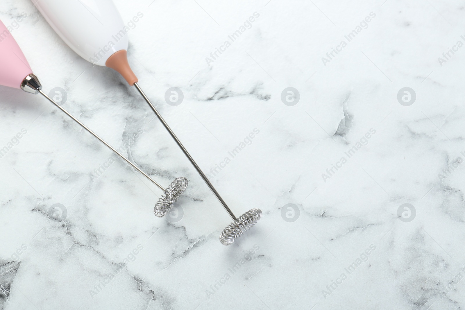 Photo of Milk frother wands on white marble table, top view. Space for text