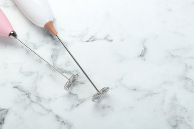 Milk frother wands on white marble table, top view. Space for text