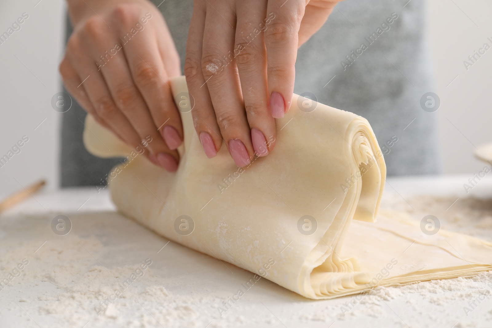 Photo of Making tasty baklava. Woman with dough at table, closeup