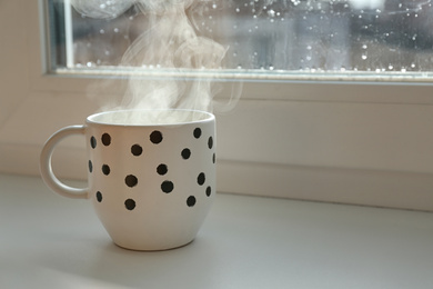 Photo of Cup of hot drink near window on rainy day.  Space for text