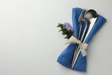 Photo of Stylish setting with cutlery and napkin on white textured table, top view. Space for text