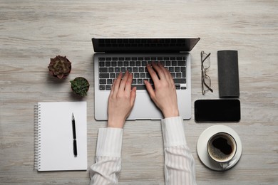 Photo of Woman using laptop at wooden table, top view