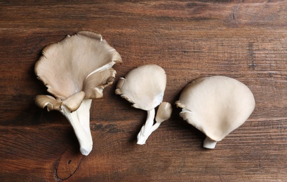Photo of Delicious organic oyster mushrooms on wooden background, flat lay