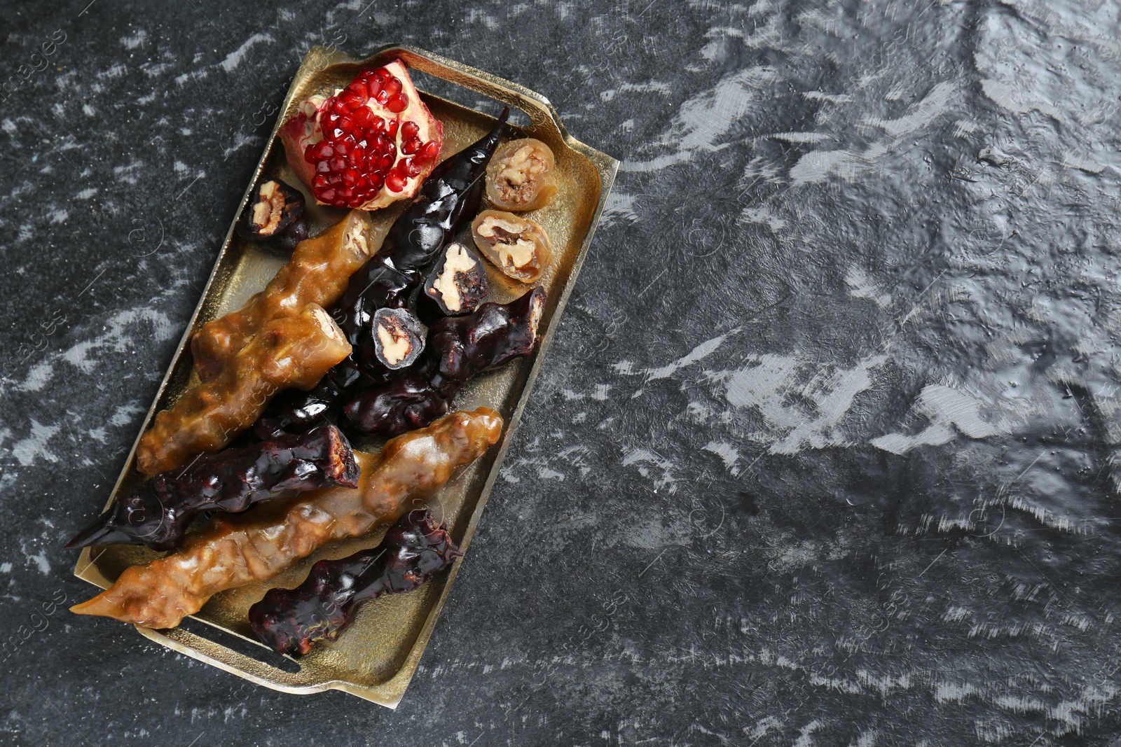 Photo of Delicious sweet churchkhelas and pomegranate on textured table, top view. Space for text