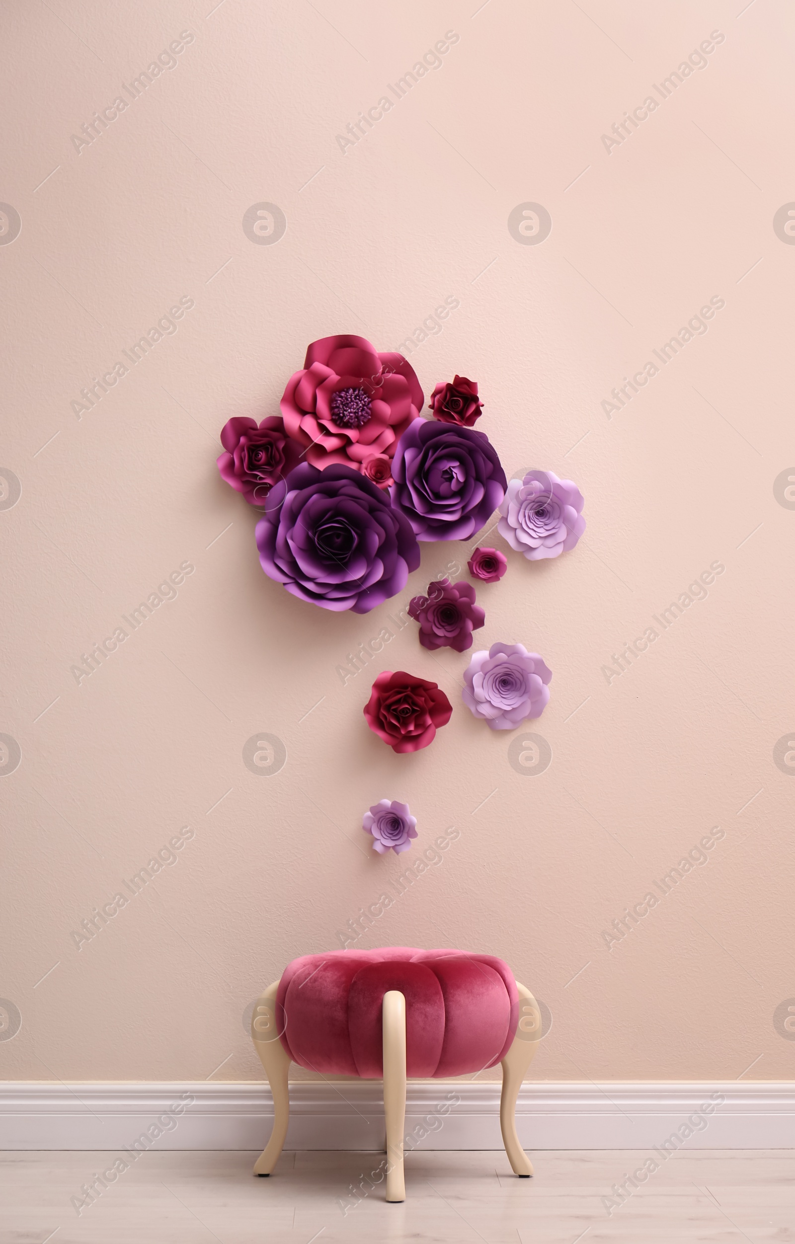 Photo of Stool near wall with floral decor in room. Interior design