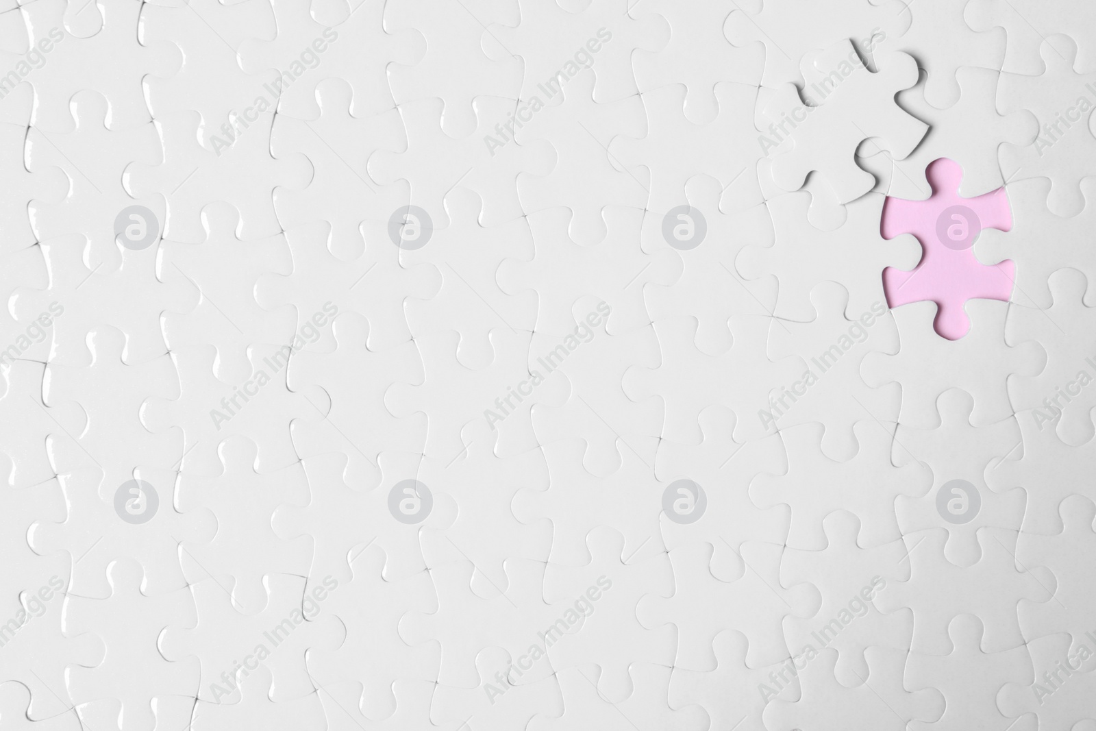 Photo of Blank white puzzle with separated piece on pink background, top view. Space for text