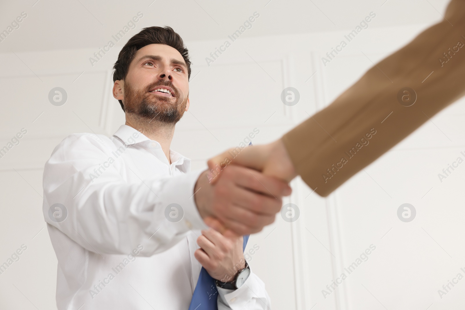 Photo of Human resources manager shaking hands with applicant during job interview in office