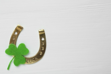 Photo of Decorative clover leaf and horseshoe on white wooden background, flat lay with space for text. St. Patrick's Day celebration