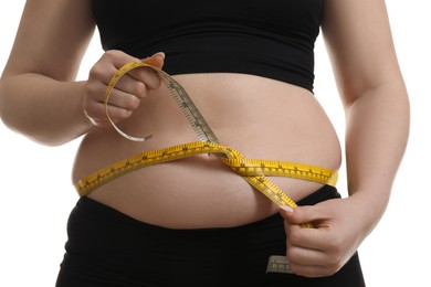 Woman measuring belly with tape on white background, closeup. Overweight problem