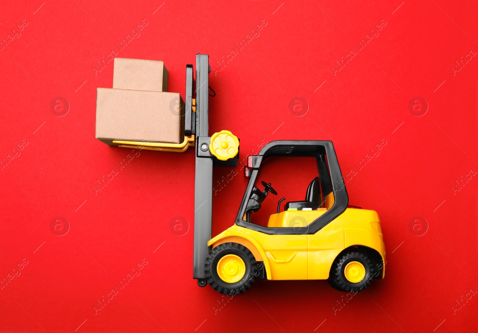 Photo of Top view of toy forklift with boxes on red background. Logistics and wholesale concept