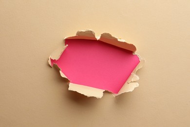 Hole in light beige paper on pink background