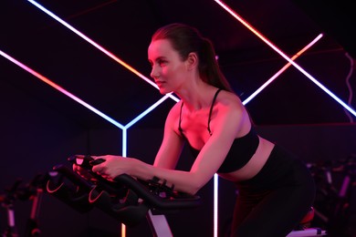 Photo of Young woman training on exercise bike in fitness club