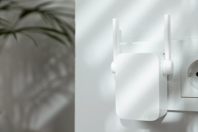 Photo of Wireless Wi-Fi repeater on white wall indoors, space for text