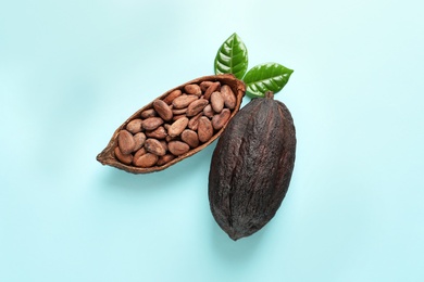 Cocoa pods and beans on light blue background, flat lay