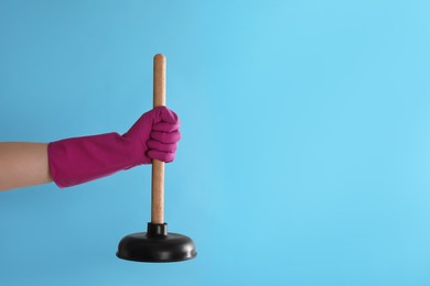 Photo of Woman holding plunger on turquoise background, closeup. Space for text
