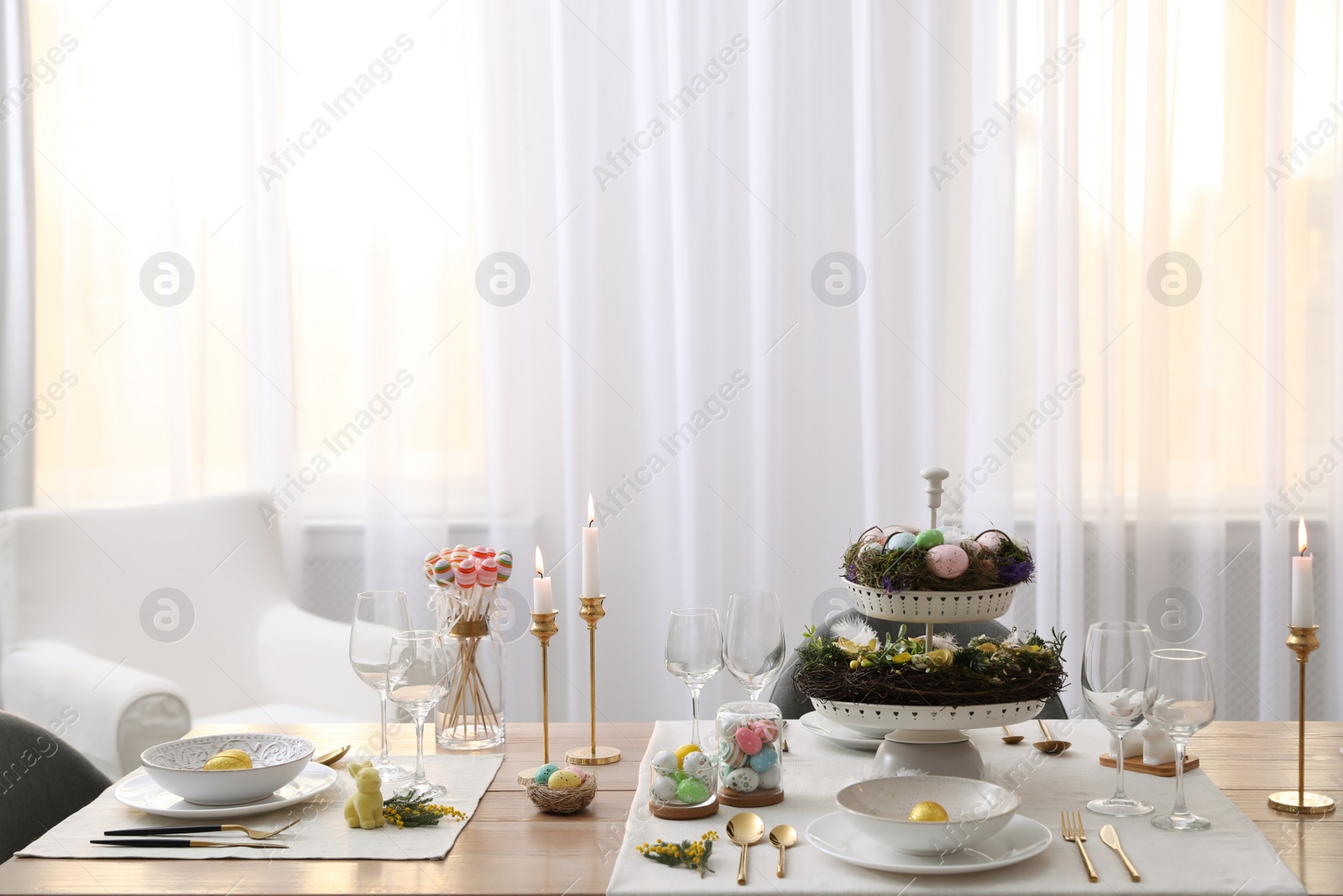 Photo of Beautiful Easter table setting with burning candles and floral decor indoors