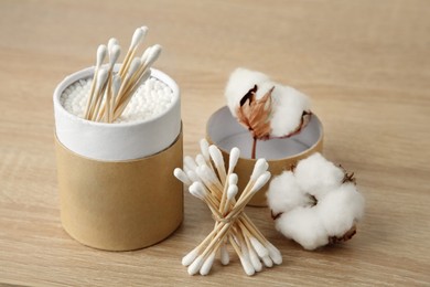 Photo of Cotton swabs and flowers on wooden table, closeup