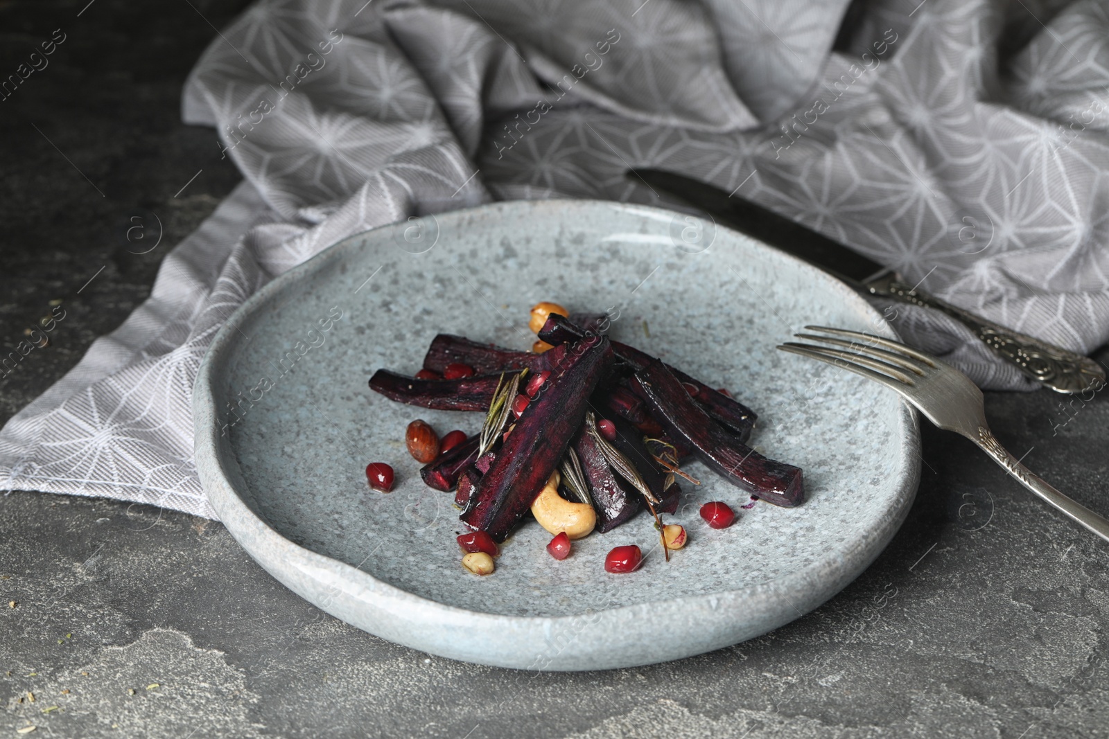 Photo of Tasty baked black carrot on grey table, closeup