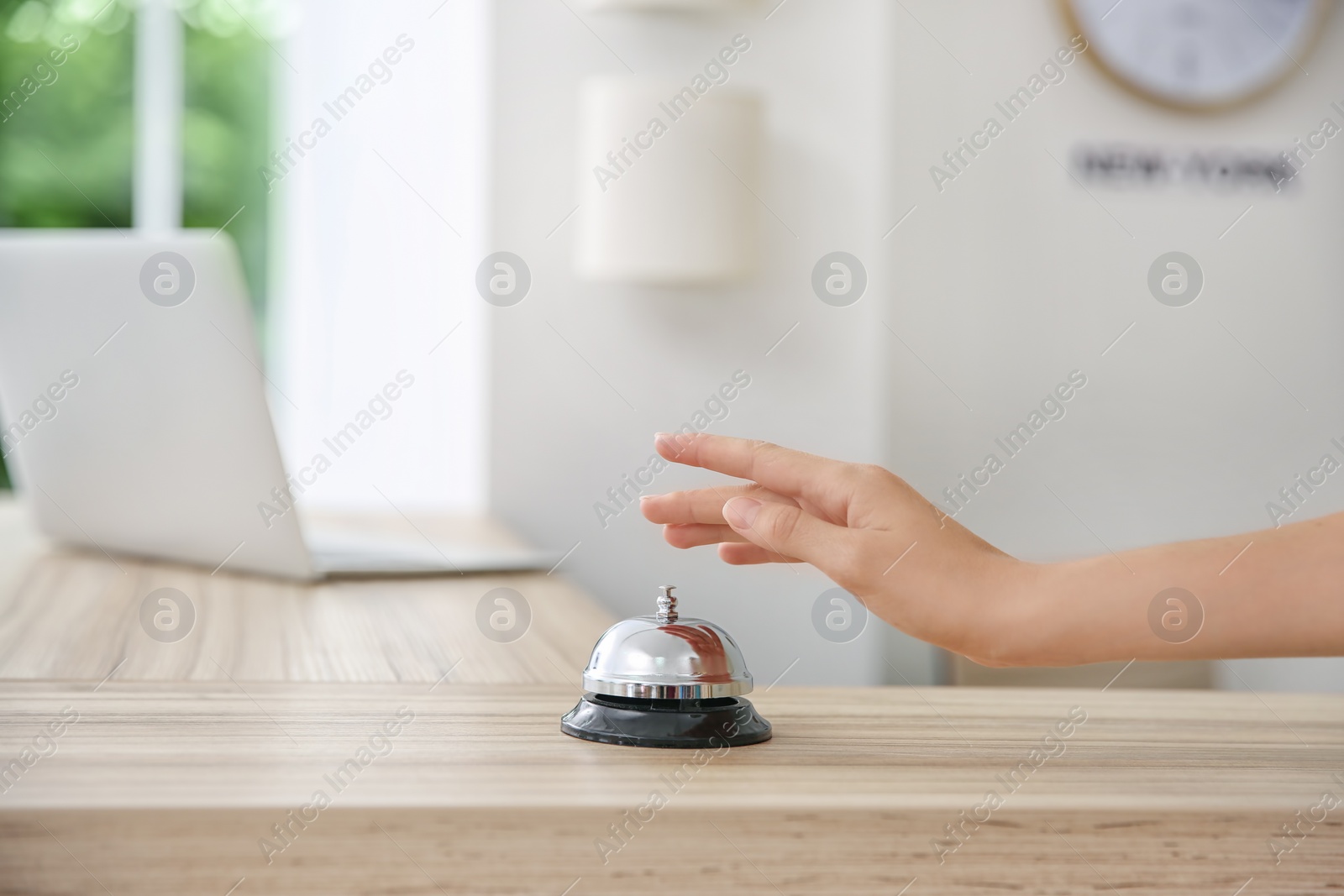 Photo of Woman ringing service bell on reception desk in hotel, closeup