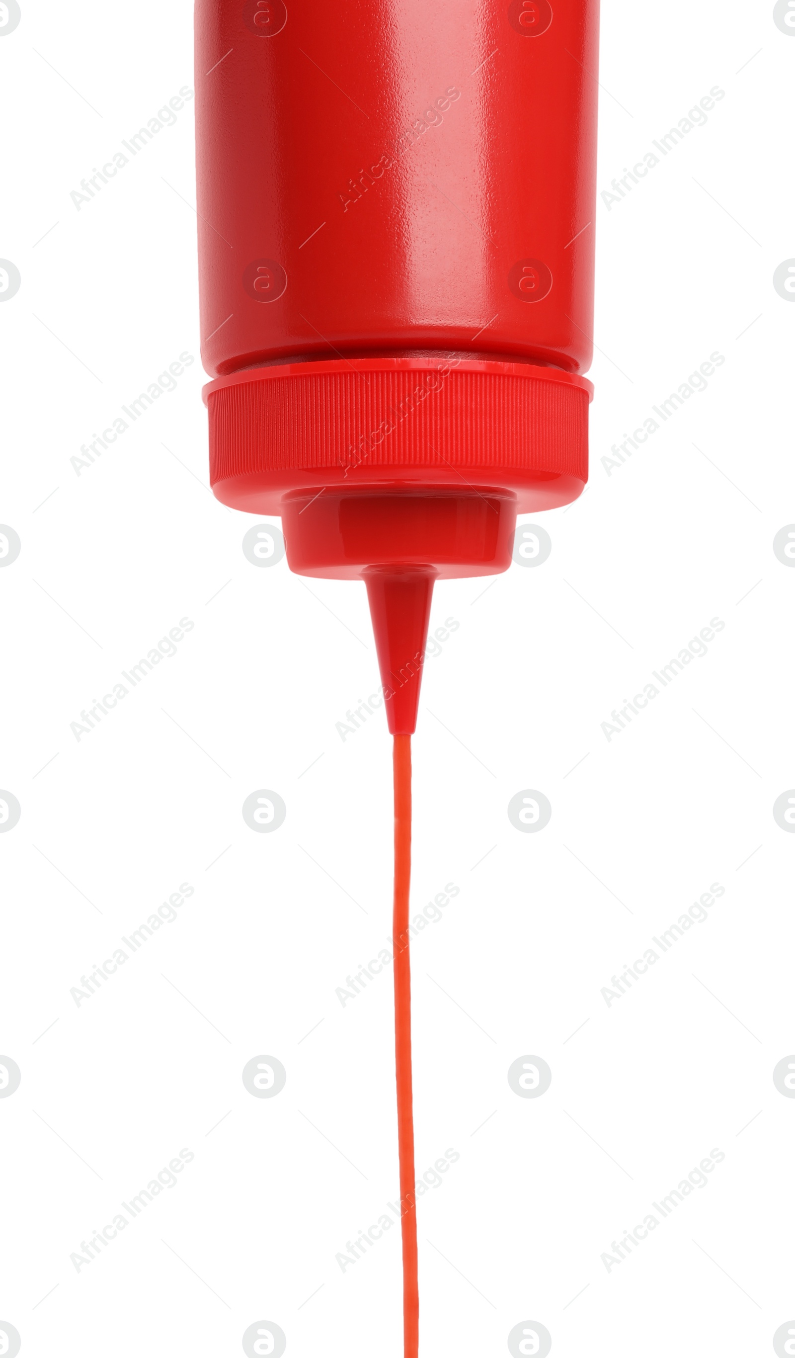 Photo of Pouring tasty red ketchup from bottle isolated on white