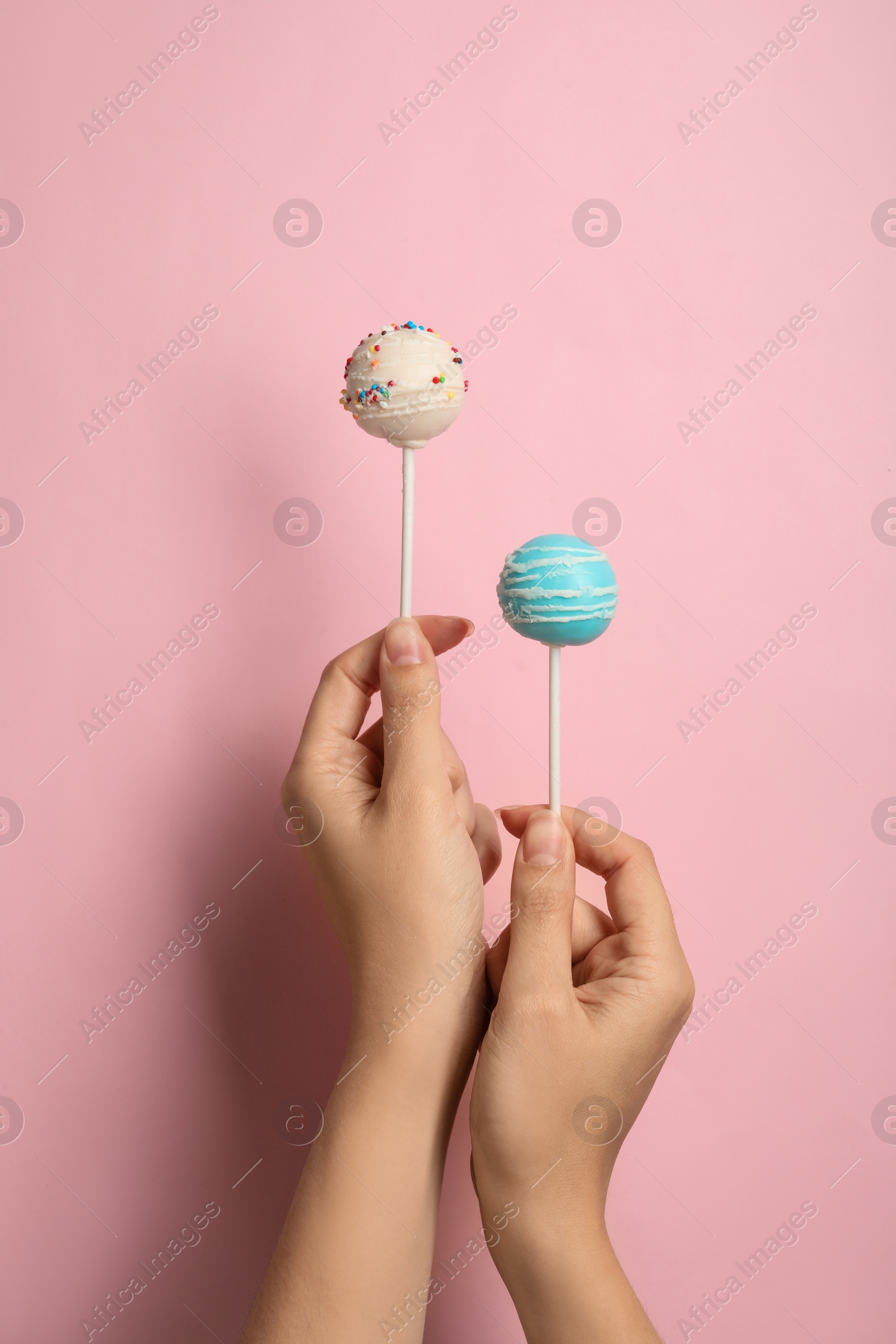 Photo of Woman holding bright delicious cake pops on color background, closeup