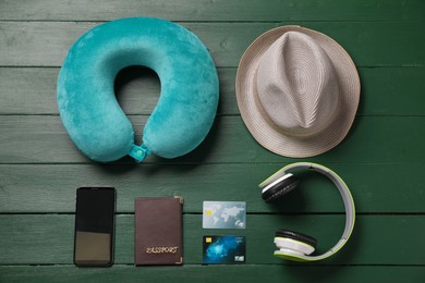 Photo of Flat lay composition with turquoise travel pillow and smartphone on green wooden background