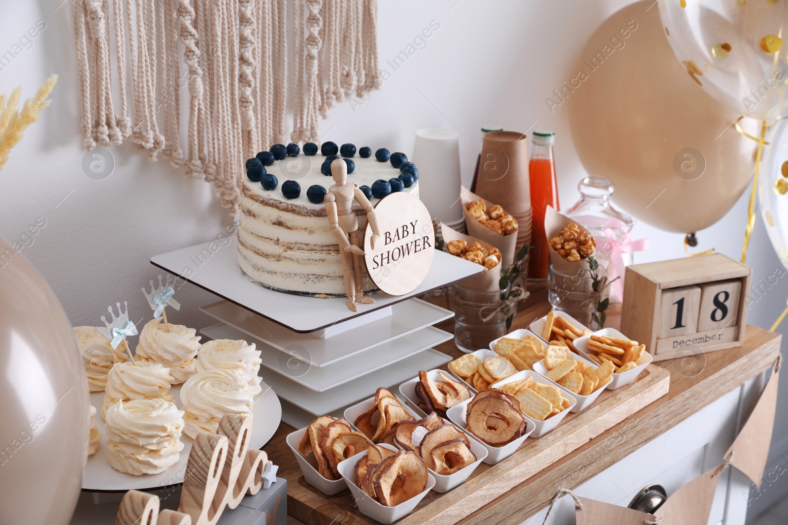 Photo of Baby shower party. Different delicious treats on wooden table and decor near light wall