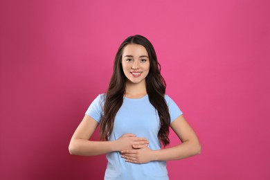 Photo of Happy healthy woman touching her belly on pink background