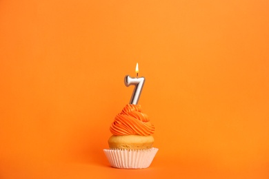 Photo of Birthday cupcake with number seven candle on orange background