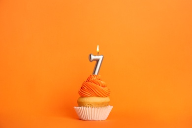 Birthday cupcake with number seven candle on orange background