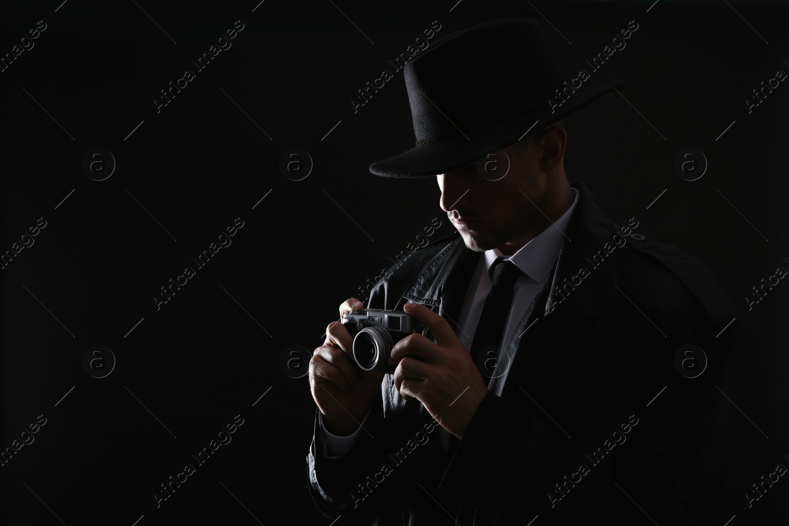 Photo of Old fashioned detective with camera on dark background. Space for text