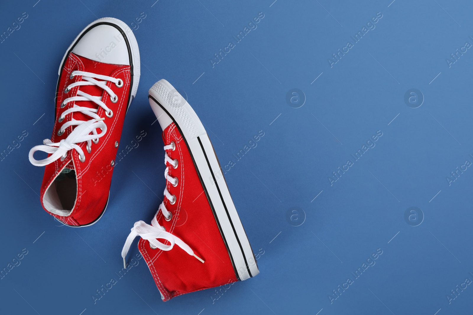 Photo of Pair of trendy sneakers on blue background, flat lay. Space for text